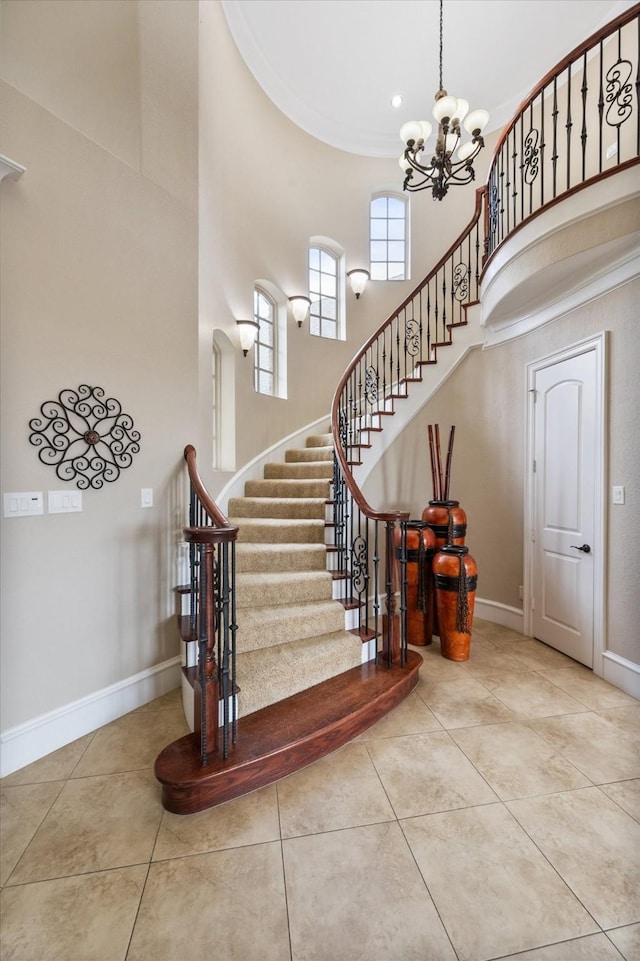 staircase with an inviting chandelier, a high ceiling, baseboards, and tile patterned floors