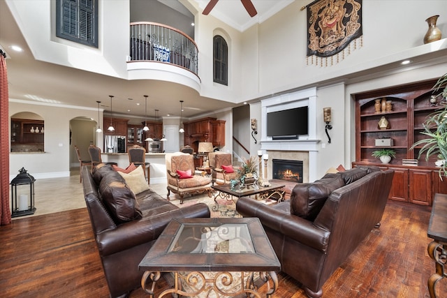 living room with dark hardwood / wood-style floors, ornamental molding, a fireplace, and a towering ceiling