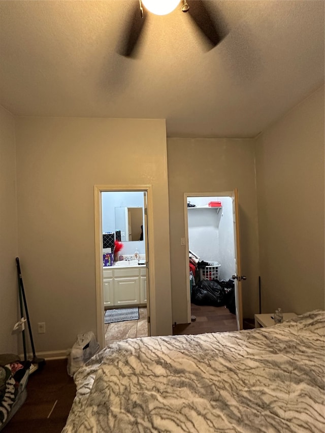 unfurnished bedroom featuring a walk in closet, a textured ceiling, ceiling fan, and ensuite bath