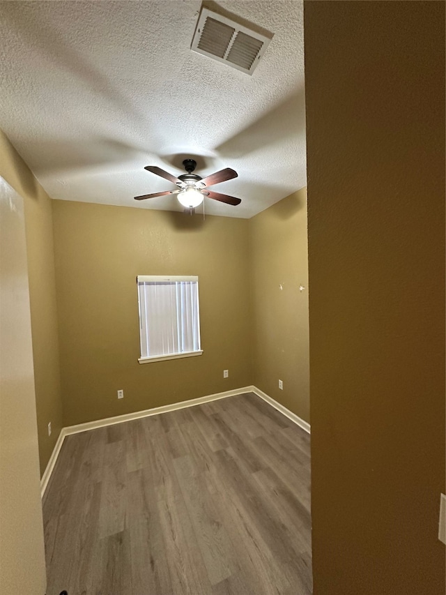 empty room with a textured ceiling, hardwood / wood-style flooring, and ceiling fan