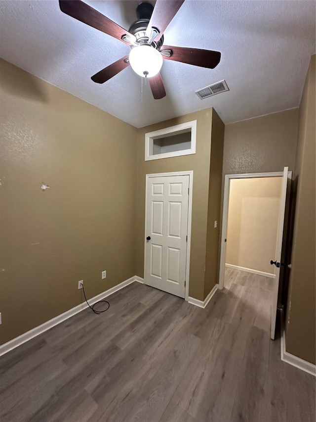 unfurnished bedroom with hardwood / wood-style flooring, a textured ceiling, and ceiling fan