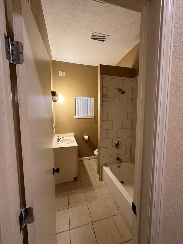 full bathroom with tile patterned floors, vanity, a textured ceiling, tiled shower / bath combo, and toilet