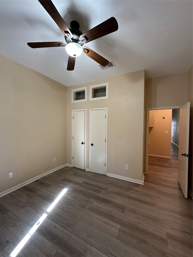 unfurnished bedroom featuring ceiling fan, dark hardwood / wood-style floors, and a textured ceiling