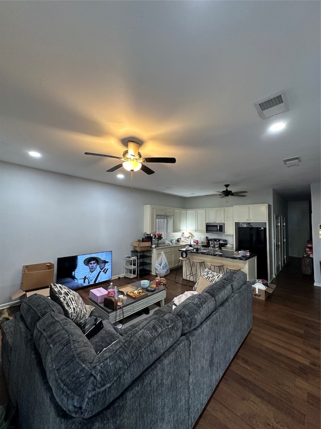 living room featuring dark wood-type flooring and ceiling fan