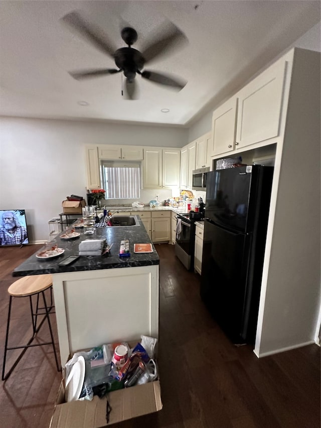 kitchen featuring stainless steel appliances, white cabinetry, a kitchen bar, dark hardwood / wood-style floors, and ceiling fan