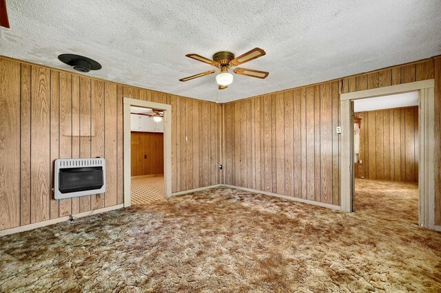 unfurnished room featuring a textured ceiling, heating unit, ceiling fan, and carpet