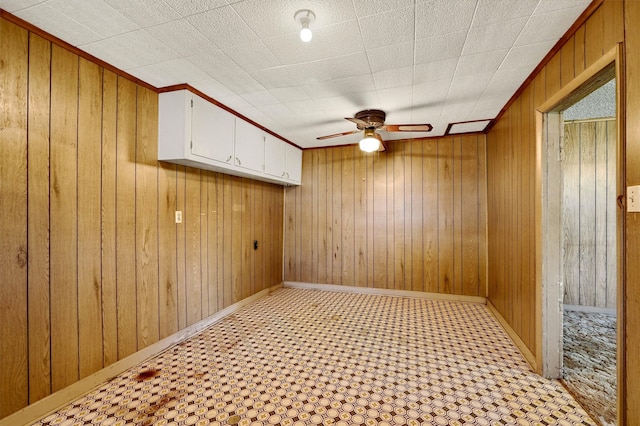 spare room featuring ceiling fan and wooden walls