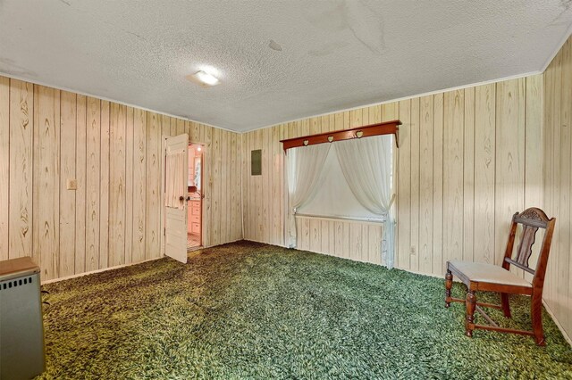 unfurnished room with wood walls, carpet, and a textured ceiling