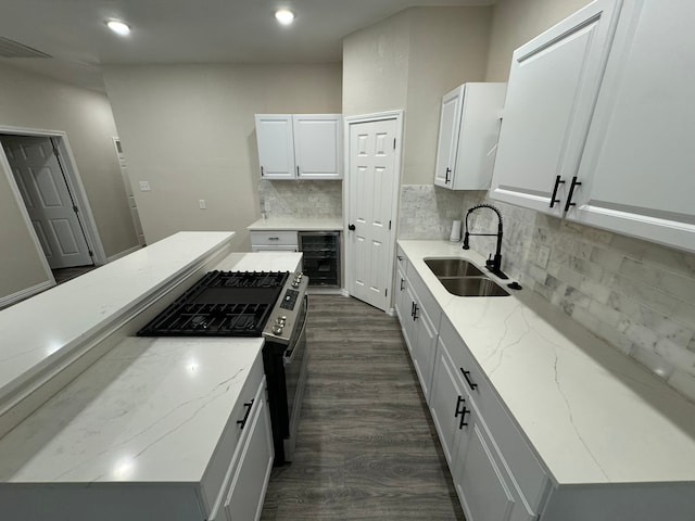 kitchen featuring wine cooler, white cabinets, dark hardwood / wood-style flooring, gas range, and sink