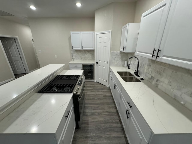 kitchen featuring a sink, gas range, decorative backsplash, beverage cooler, and dark wood-type flooring