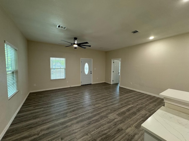 unfurnished living room featuring baseboards, visible vents, and dark wood-style flooring