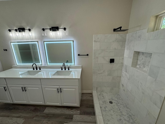 full bath with walk in shower, wood finished floors, a sink, and double vanity