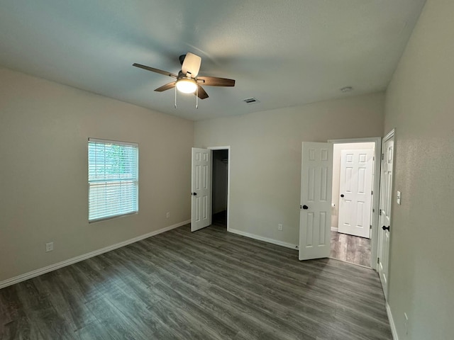 unfurnished bedroom featuring a ceiling fan, baseboards, dark wood-style flooring, and visible vents