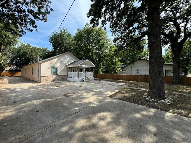 view of front of property with concrete driveway, fence, and a porch