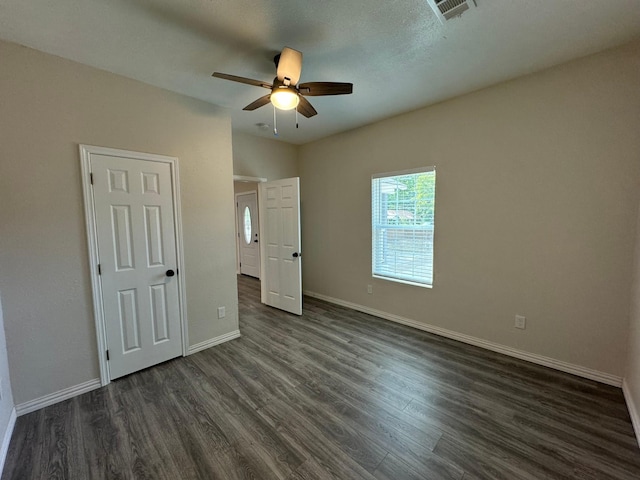 unfurnished bedroom with visible vents, baseboards, dark wood-style floors, and ceiling fan