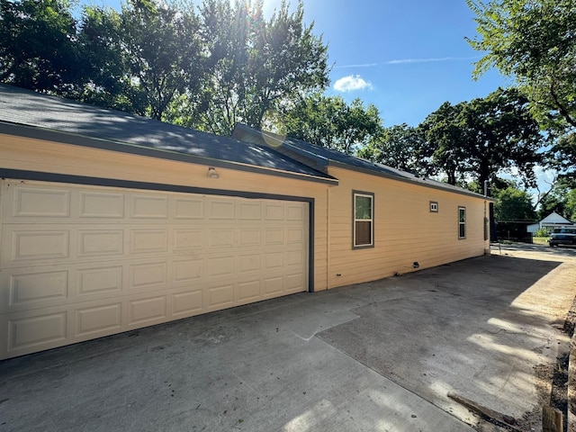 view of property exterior featuring an attached garage and driveway