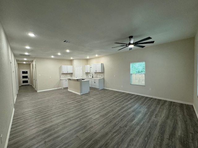 unfurnished living room with dark hardwood / wood-style floors, ceiling fan, and sink