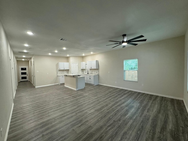 unfurnished living room with a sink, dark wood finished floors, baseboards, visible vents, and recessed lighting