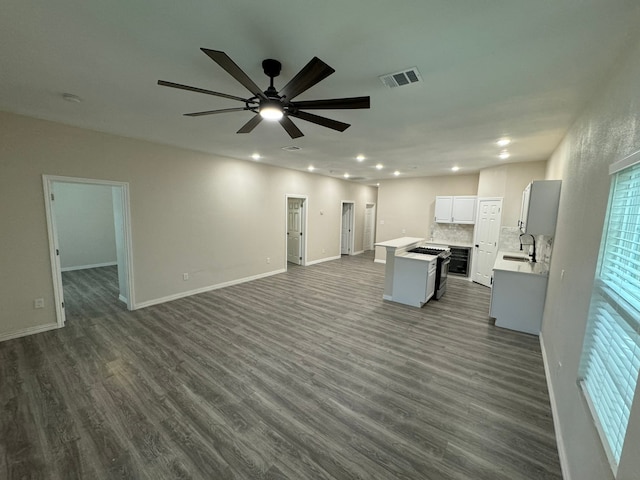 interior space with white cabinetry, dark wood-type flooring, a kitchen island, ceiling fan, and sink