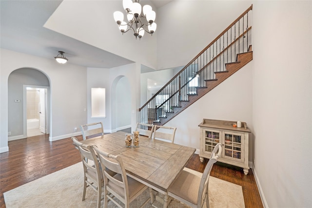 dining area with dark wood-type flooring and an inviting chandelier