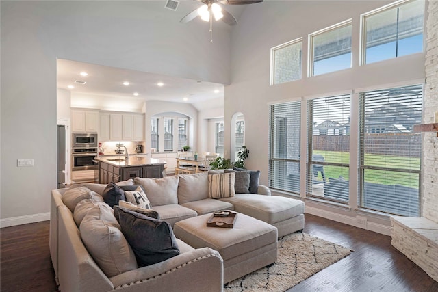 living room with a healthy amount of sunlight, sink, ceiling fan, and dark hardwood / wood-style floors