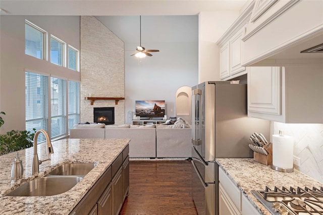 kitchen featuring white cabinetry, sink, a stone fireplace, dark wood-type flooring, and ceiling fan