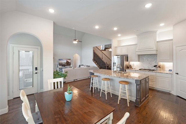 dining area featuring dark wood-type flooring, ceiling fan, high vaulted ceiling, and sink