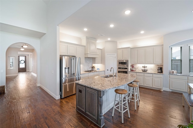 kitchen with white cabinets, stainless steel appliances, a kitchen island with sink, and sink