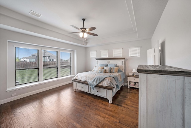 bedroom with dark hardwood / wood-style flooring, ceiling fan, and a raised ceiling