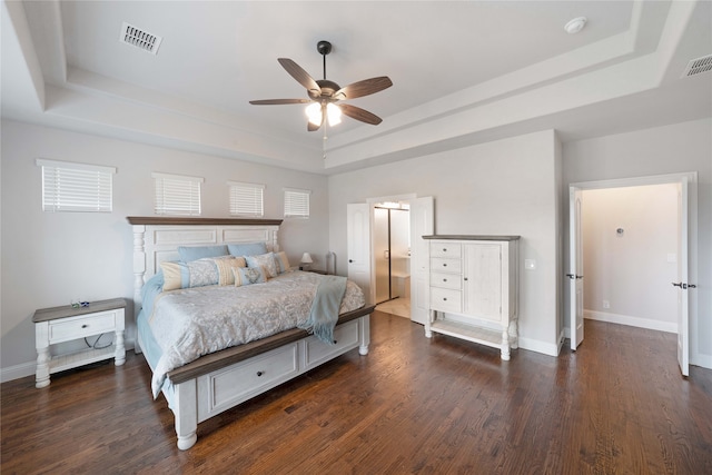 bedroom with dark hardwood / wood-style flooring, ceiling fan, and a tray ceiling