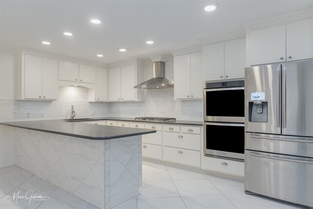 kitchen with ceiling fan, stainless steel appliances, wall chimney range hood, kitchen peninsula, and white cabinets