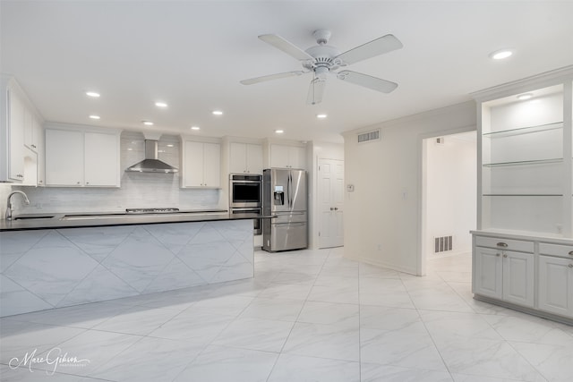 kitchen featuring wall chimney exhaust hood, appliances with stainless steel finishes, a sink, and visible vents