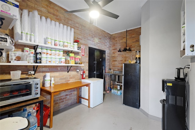 interior space featuring fridge, brick wall, stainless steel refrigerator, and ceiling fan