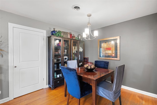 dining space with hardwood / wood-style flooring and an inviting chandelier