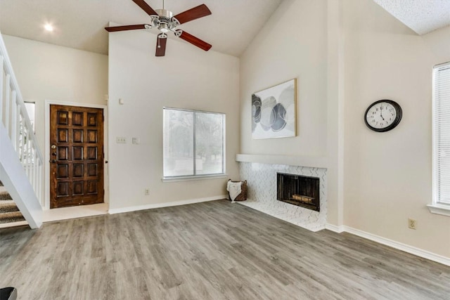 unfurnished living room featuring ceiling fan, a fireplace, high vaulted ceiling, and hardwood / wood-style flooring