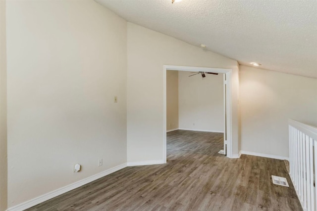 spare room featuring a textured ceiling, ceiling fan, hardwood / wood-style floors, and vaulted ceiling