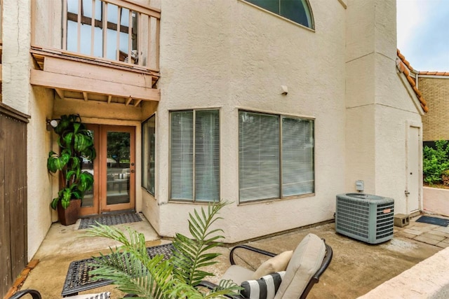 view of exterior entry featuring cooling unit and a patio