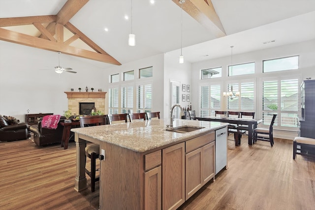 kitchen featuring light hardwood / wood-style floors, high vaulted ceiling, pendant lighting, a kitchen island with sink, and sink