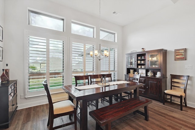 dining area with an inviting chandelier, dark hardwood / wood-style floors, and a high ceiling