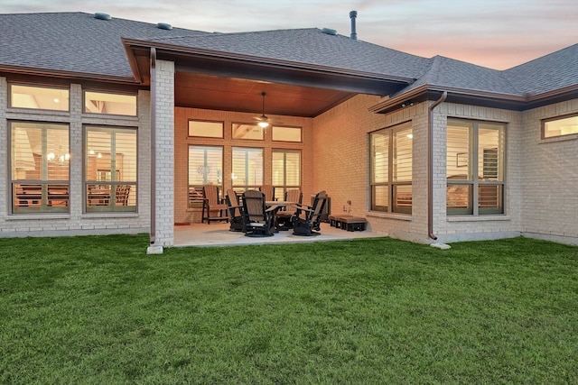 back house at dusk featuring ceiling fan, a yard, and a patio