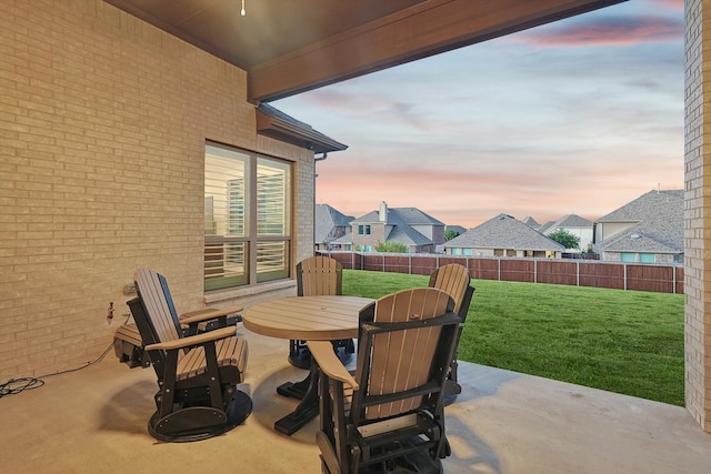 patio terrace at dusk featuring a yard