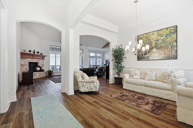 living room featuring ornamental molding, a fireplace, a chandelier, and dark hardwood / wood-style flooring