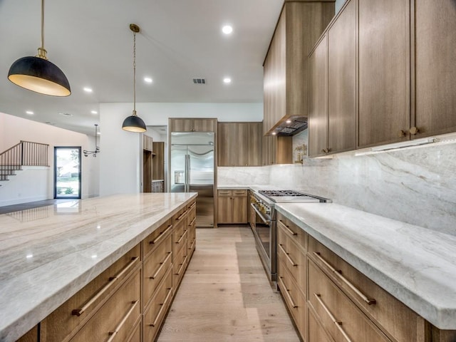 kitchen with tasteful backsplash, light stone countertops, pendant lighting, and high end appliances