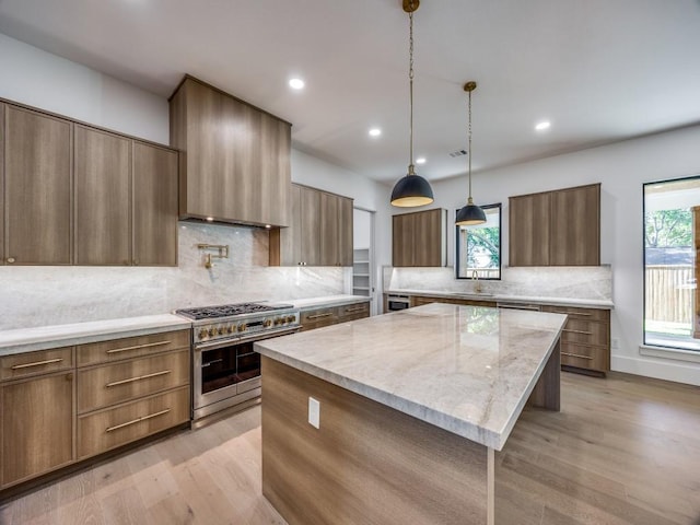 kitchen featuring high end stove, a center island, light hardwood / wood-style flooring, and tasteful backsplash