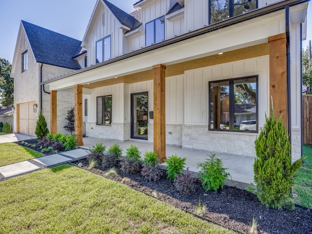 property entrance with a lawn, a garage, and covered porch