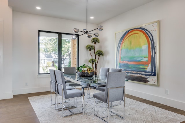 dining space with a healthy amount of sunlight, a notable chandelier, and wood-type flooring