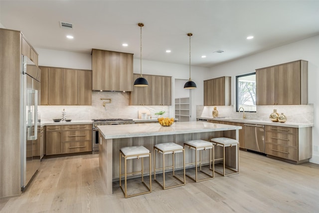 kitchen featuring a kitchen bar, backsplash, wall chimney exhaust hood, high quality appliances, and a kitchen island