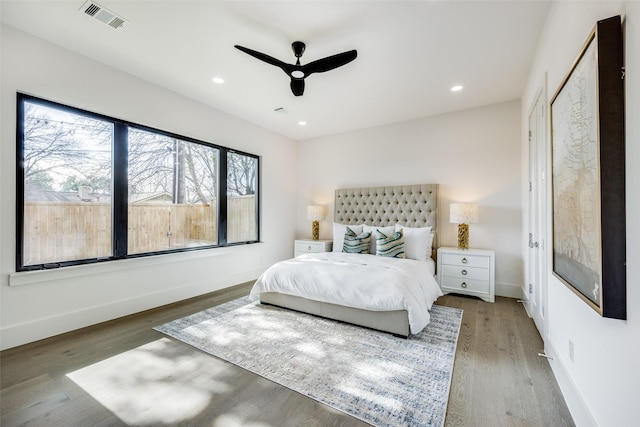 bedroom with hardwood / wood-style flooring, ceiling fan, and multiple windows