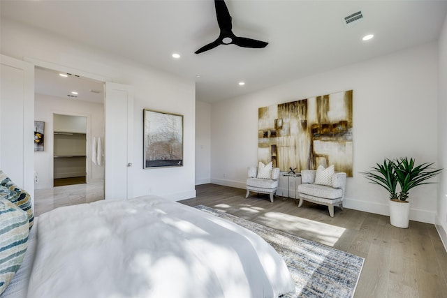 bedroom with ceiling fan, a spacious closet, and light hardwood / wood-style flooring