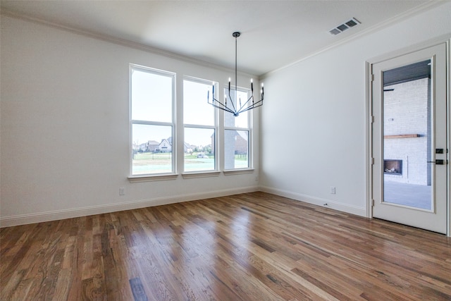 unfurnished room featuring hardwood / wood-style flooring, ornamental molding, and a notable chandelier